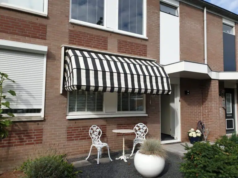 Markies met zwart-wit gestreept doek boven een raam